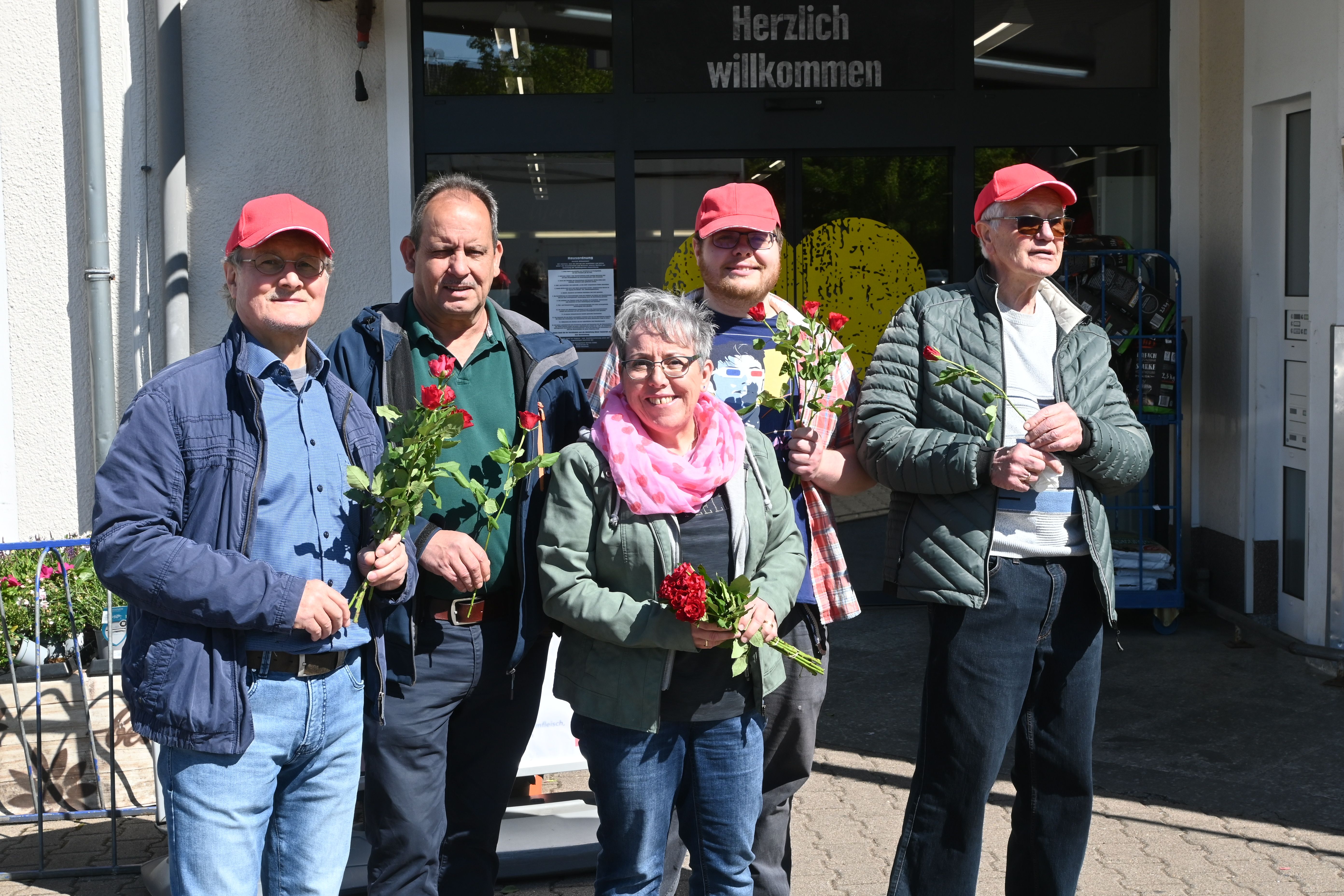 Ein Gruppenbild der fleißigen Rosenverteiler. Am sonnigen Vormittag mit Rosen in der Hand.